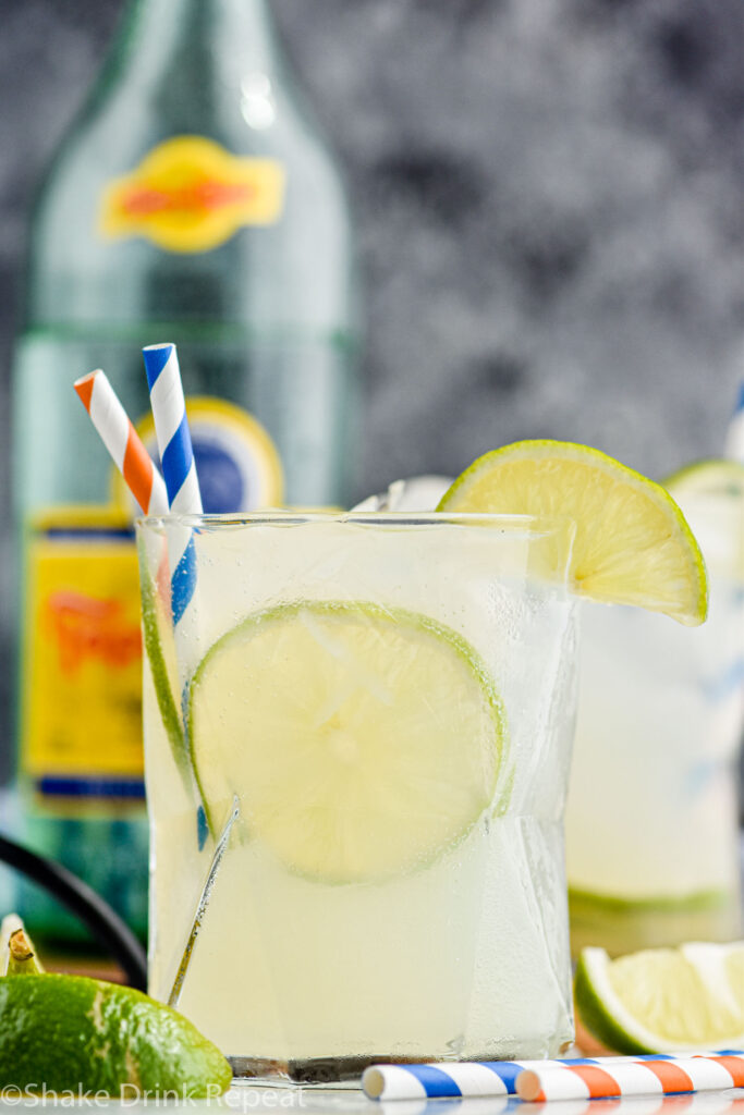 glass of Ranch Water with ice, straws, and fresh lime wedges