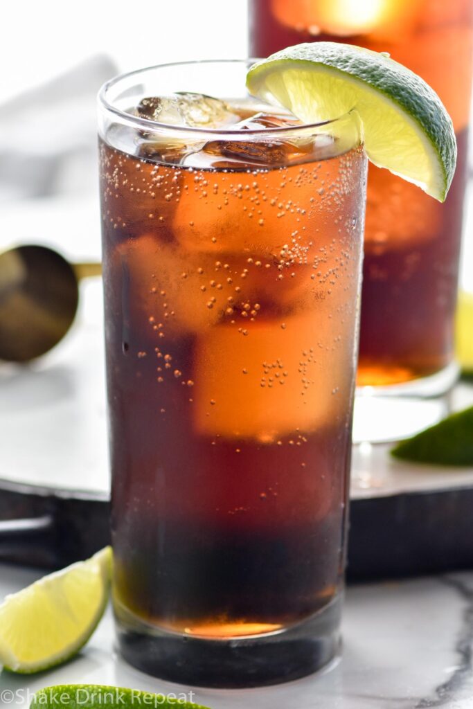 two glasses of rum and coke with ice and slice of lime garnish