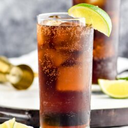 two glasses of Rum and Coke with ice and slices of lime
