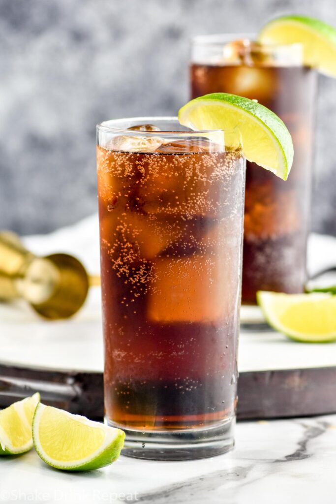 two glasses of Rum and Coke with ice and slices of lime
