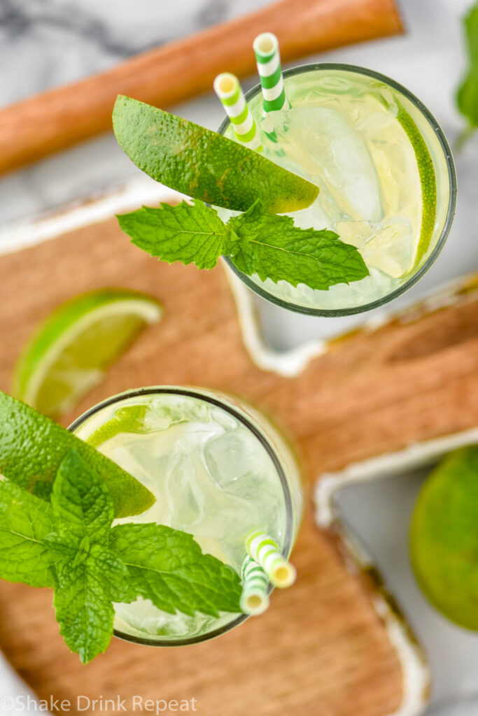 two glasses of vodka mojito with ice, straws, slices of lime, and fresh mint leaves