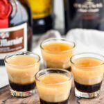 4 glasses of B-52 shots with bottles of Grand Marnier, Baileys and Kahlua in the background