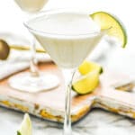 two martini glasses of Key Lime Martini recipe surrounded by slices of lime