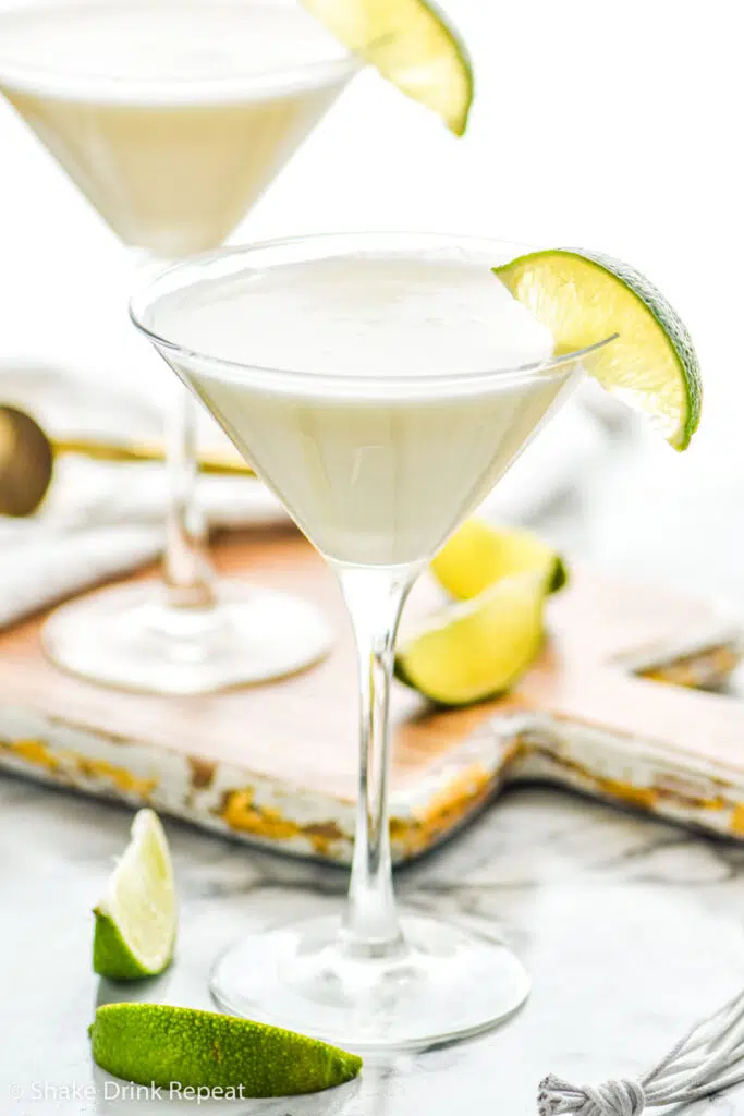 two martini glasses of Key Lime Martini recipe surrounded by slices of lime