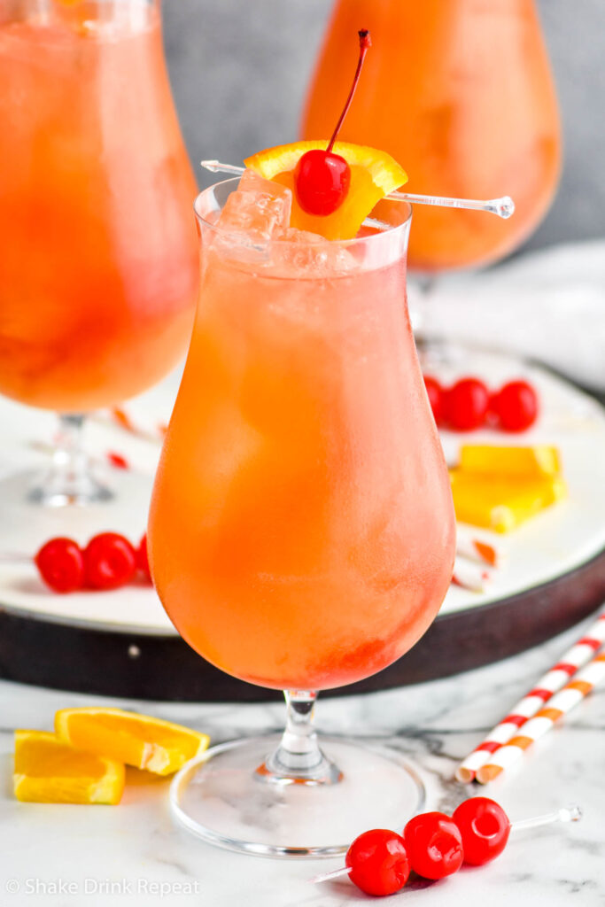 three glasses of sex on the beach cocktails with ice and garnished with maraschino cherries and orange slices