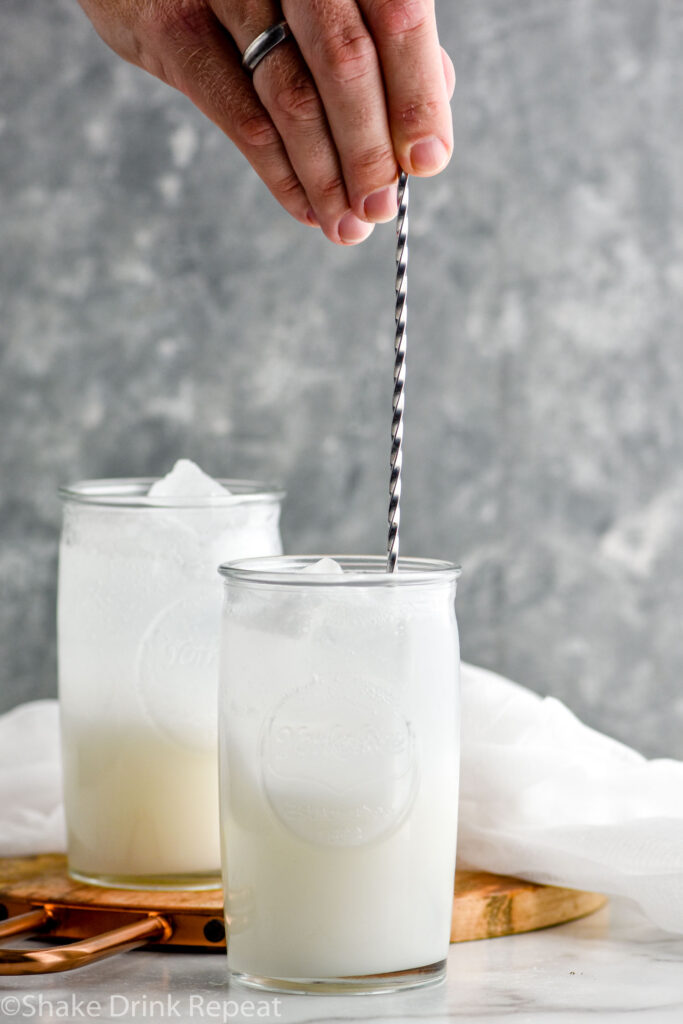 man's hand stirring Drunk Ghost cocktail with stir stick