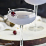 two glasses of Aviation cocktail garnished with a cherry