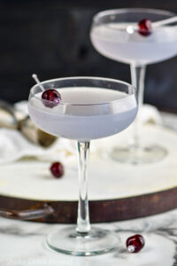 two glasses of Aviation cocktail garnished with a cherry