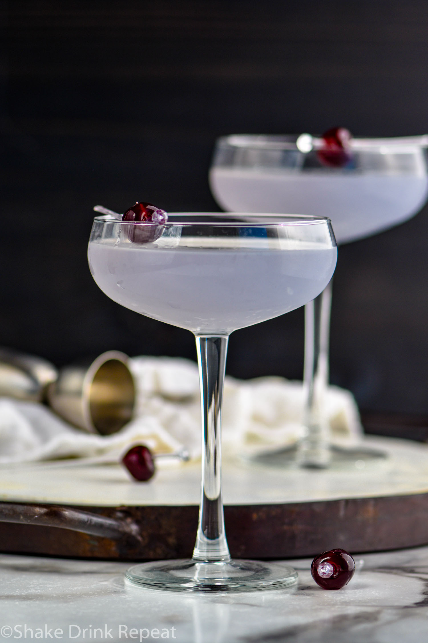 two glasses of Aviation Cocktail garnished with a cherry