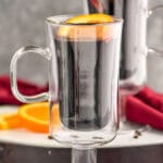 two mugs of Mulled Wine with orange slices and cinnamon sticks