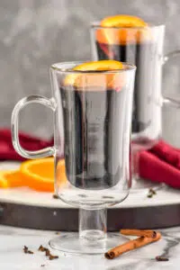 two mugs of Mulled Wine with orange slices and cinnamon sticks