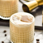 two glasses of Colorado Bulldog with ice surrounded by coffee beans and a jigger