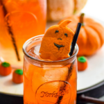 glass of drunk pumpkin cocktail with ice, straw and pumpkin candies