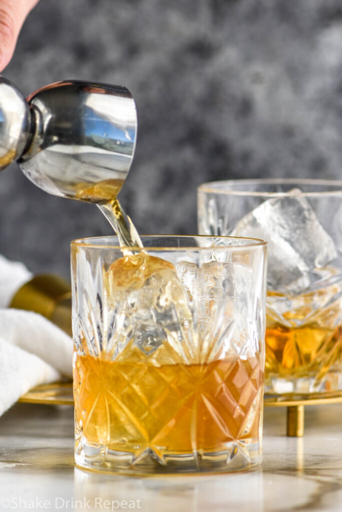 jigger of Amaretto pouring into two old fashioned glasses of French Connection cocktail recipe with ice