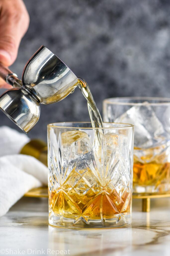 jigger of Amaretto pouring into a glass of French Connection cocktail recipe with ice