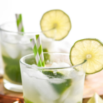 two glasses of Caipirinha recipe with ice, limes, and straws