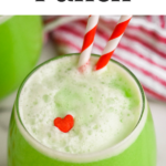 glass of Grinch Punch recipe with two straws and a candy heart garnish