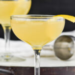 two coupe glasses of Between the Sheets recipe garnished with fresh lemon peel