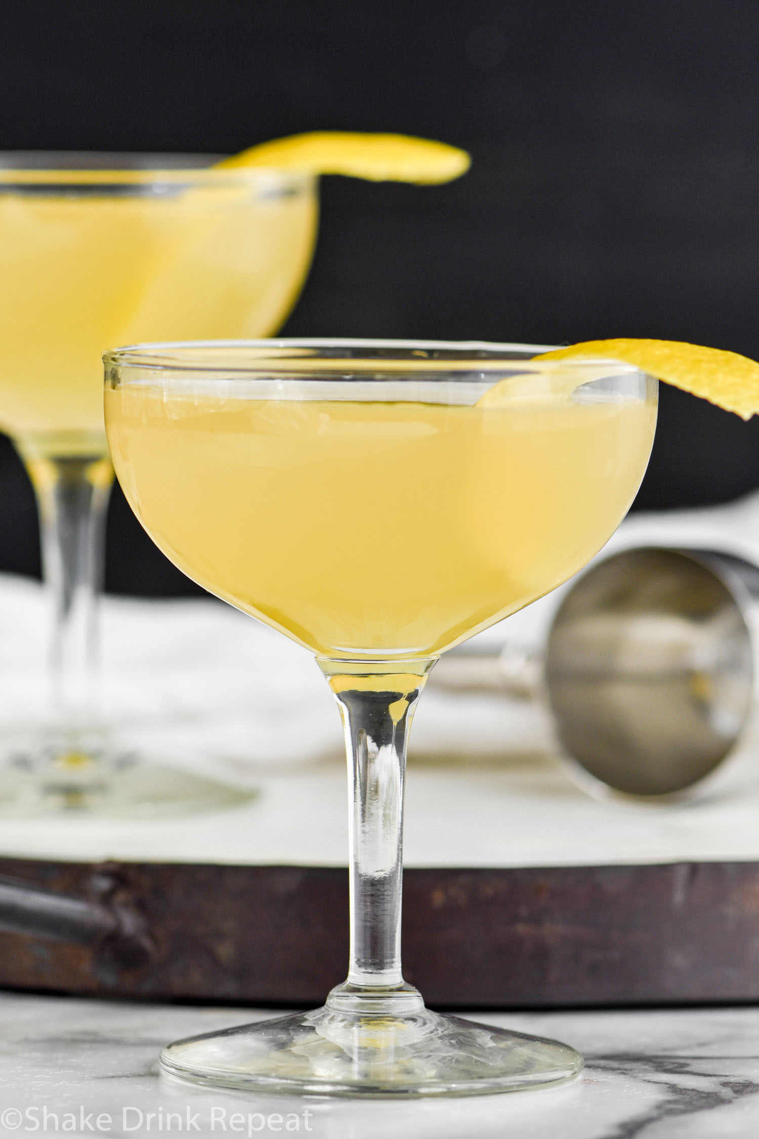 two coupe glasses of Between the Sheets recipe garnished with fresh lemon peel