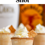 shot glasses of Cinnamon Toast Crunch Shot recipe with cinnamon sugar rim and whipped cream topping and bottles of RumChata and Fireball whiskey in the background