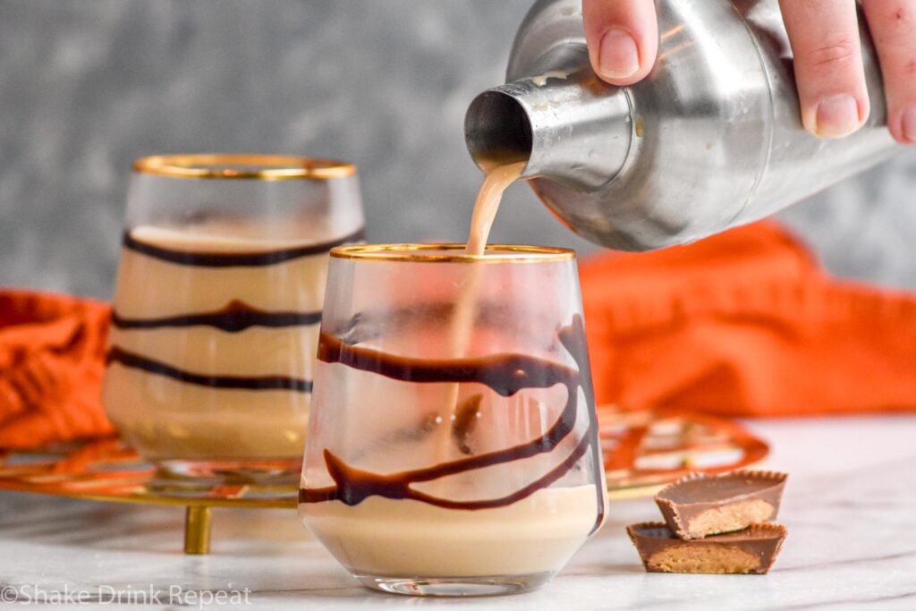 man's hand pouring a cocktail shaker of Drunk Turkey ingredients into a glass with chocolate syrup drizzle