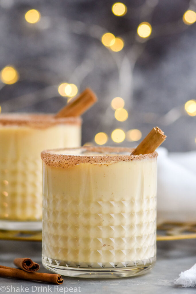 two glasses of Fireball Eggnog garnished with cinnamon sugar rim and cinnamon sticks