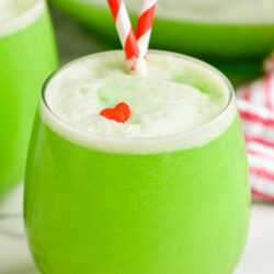 glass of Grinch Punch recipe with straws and a candy heart