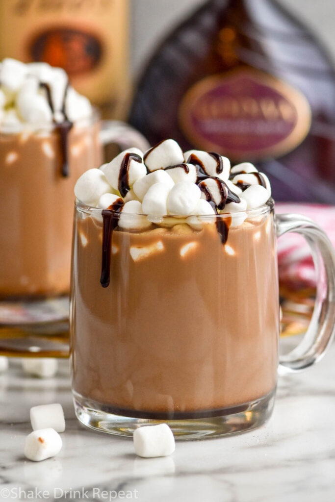 two mugs of Spiked Hot Chocolate recipe topped with marshmallows and chocolate syrup