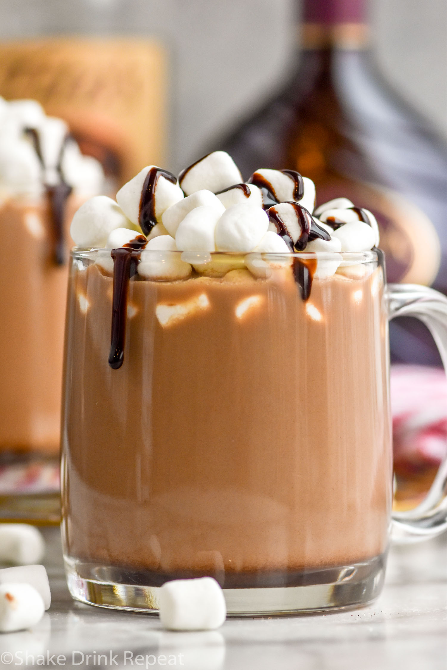mug of Spiked Hot Chocolate topped with marshmallows and chocolate syrup