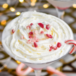 glass of Candy Cane Martini recipe topped with whipped cream and crushed candy canes