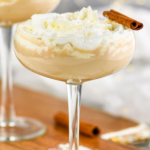 glass of Cinnamon Roll Martini topped with whipped cream and cinnamon stick