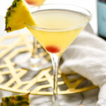 two martini glasses of Flirtini recipe garnished with fresh pineapple and a cherry