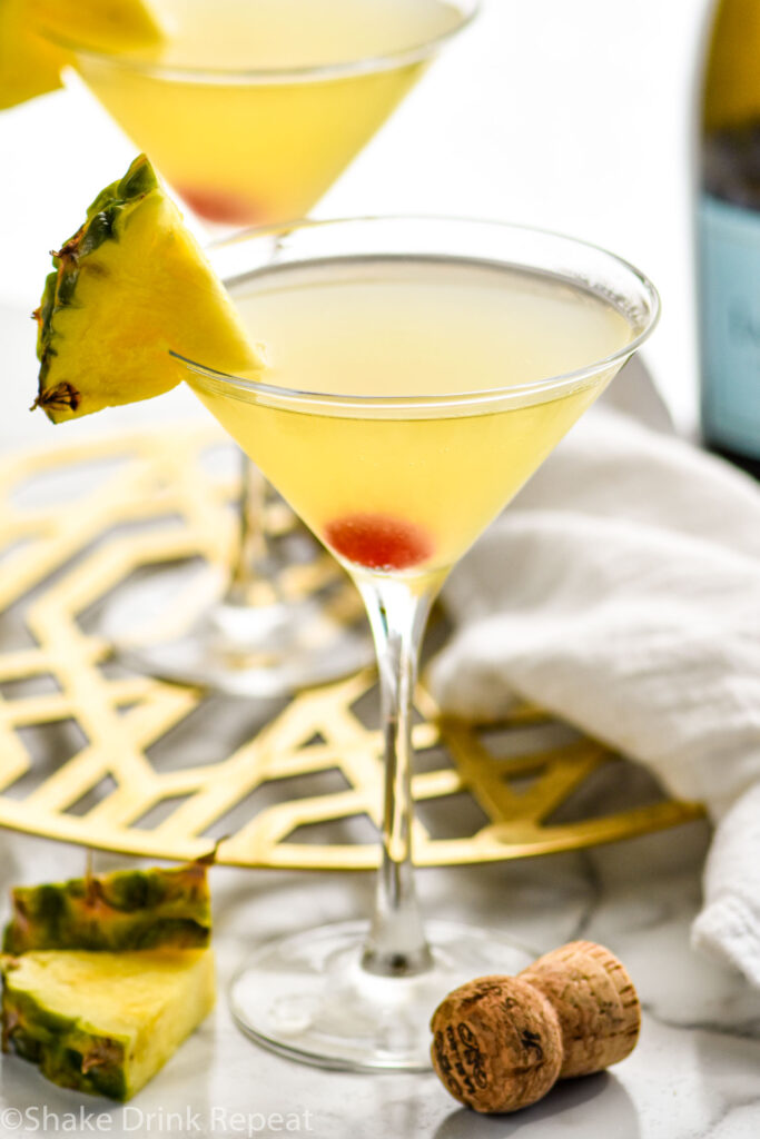 two martini glasses of Flirtini recipe garnished with fresh pineapple and a cherry