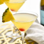 two martini glasses of Flirtini recipe garnished with fresh pineapple slices and a cherry