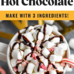 two mugs of boozy peppermint hot chocolate garnished with marshmallows, chocolate drizzle, and candy canes