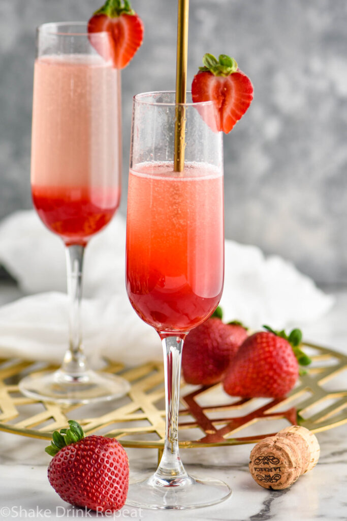 Stirring champagne flute of Rossini recipe garnished with a fresh strawberry