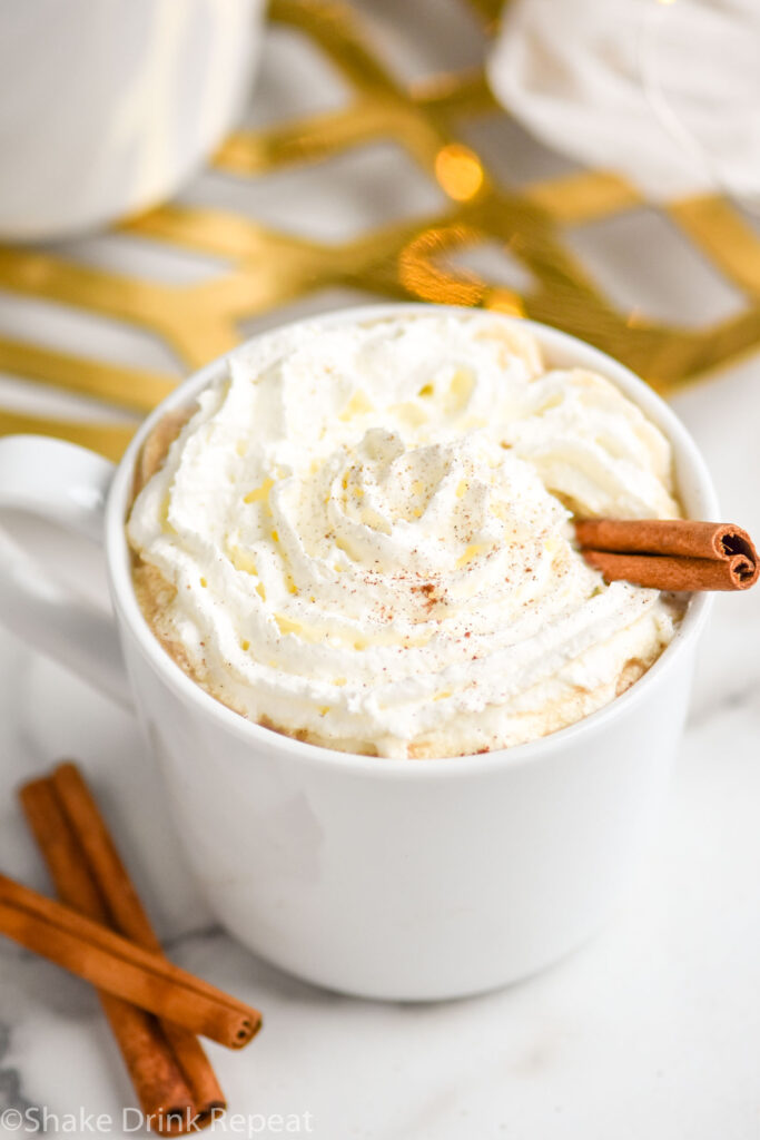 mug of Spiked Eggnog latte recipe topped with whipped cream and a cinnamon stick