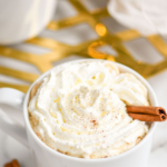 mug of Spiked Eggnog Latte topped with whipped cream and a cinnamon stick