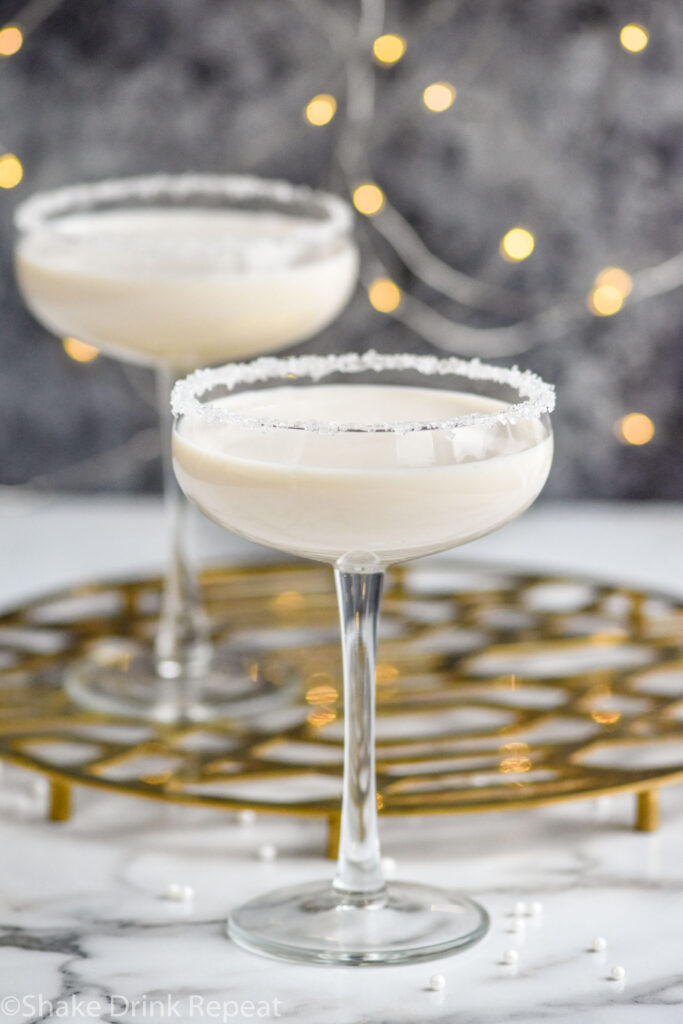 Two coupe glasses of White Christmas Martini recipe garnished with white sprinkles