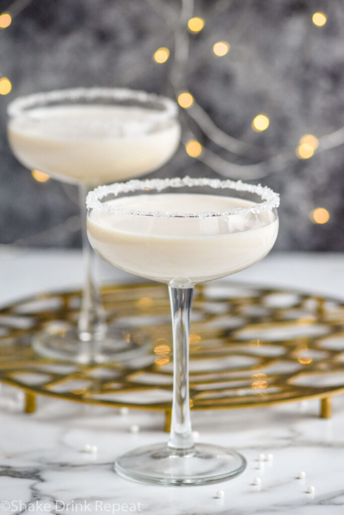 Two coupe glasses of White Christmas Martini recipe garnished with white sprinkles