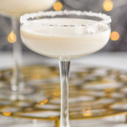 two coupe glasses of White Christmas Martini recipe garnished with white sprinkles