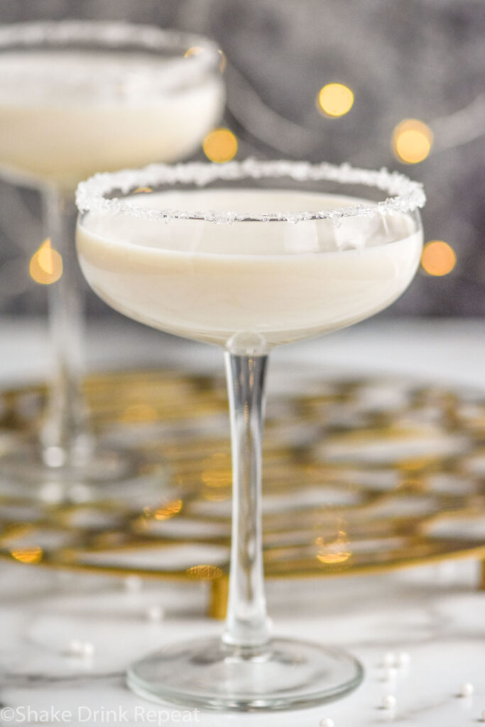 two coupe glasses of White Christmas Martini recipe garnished with white sprinkles