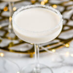 coupe glass of White Christmas Martini recipe garnished with white sprinkles