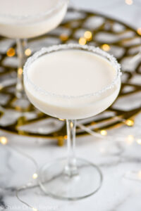 coupe glass of White Christmas Martini recipe garnished with white sprinkles