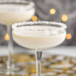 coupe glass of White Christmas Martini recipe garnished with white sprinkles