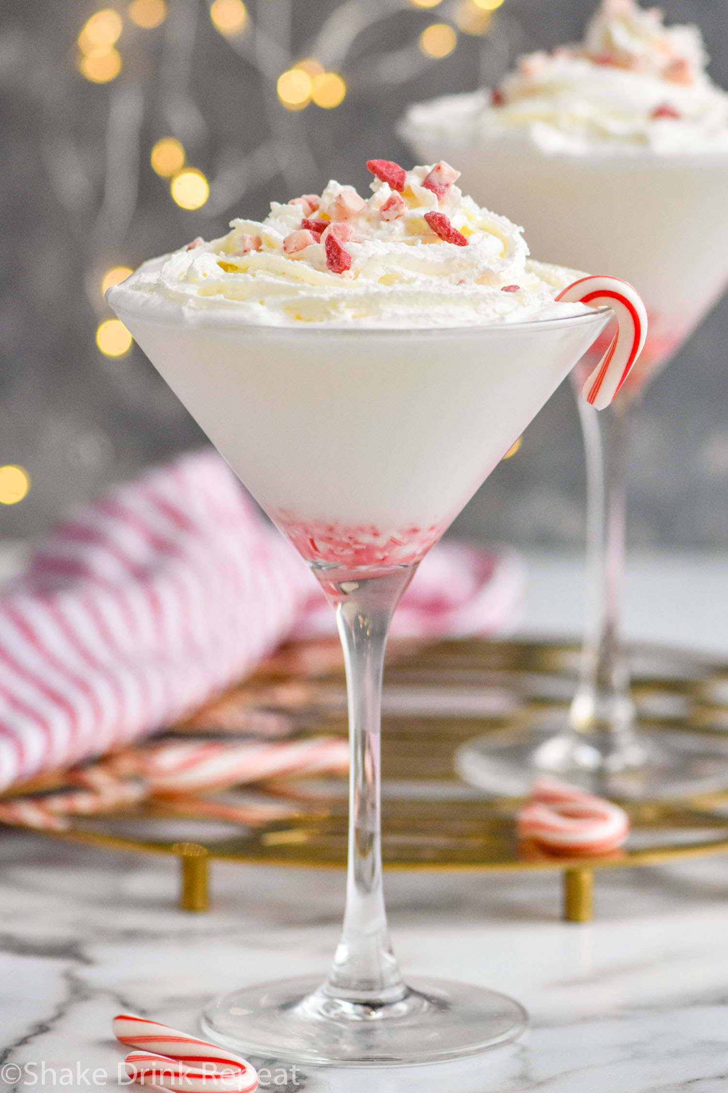 two glasses of Candy Cane Martini recipe topped with whipped cream and crushed candy canes