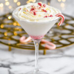 glass of Candy Cane Martini recipe garnished with whipped cream and crushed candy canes