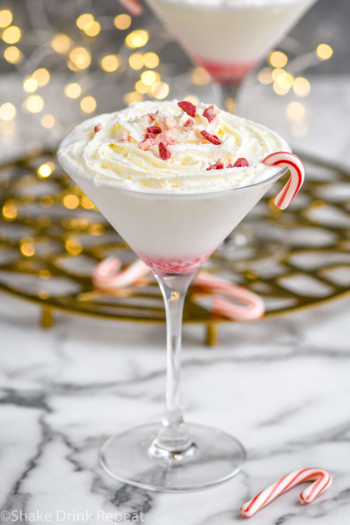 glass of Candy Cane Martini recipe garnished with whipped cream and crushed candy canes