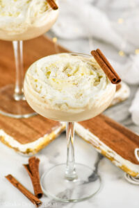 two glasses of Cinnamon Roll Martini garnished with whipped cream and cinnamon sticks