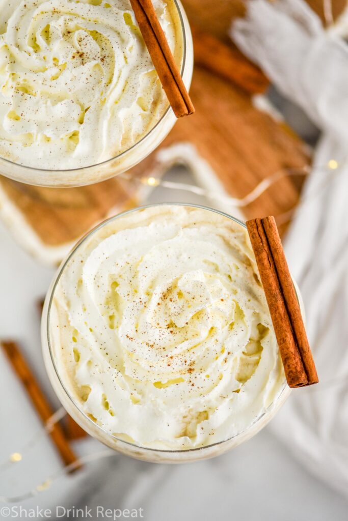 two glasses of Cinnamon Roll Martini topped with whipped cream and cinnamon sticks
